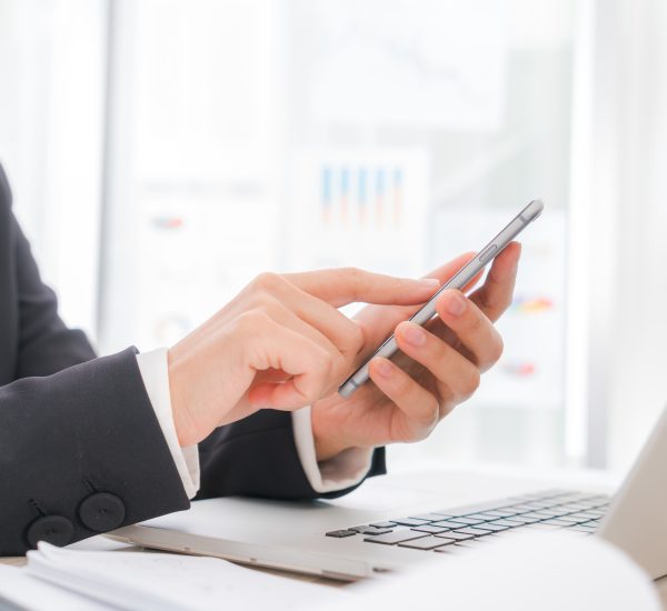 Closeup of business woman hand typing on laptop keyboard with  mobile phone